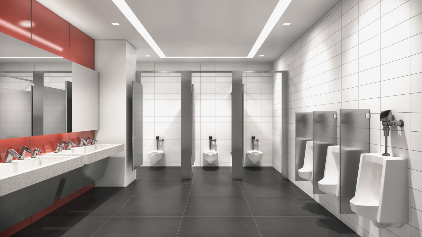 Wide angle view of public restroom with sensor faucets and flushometers installed