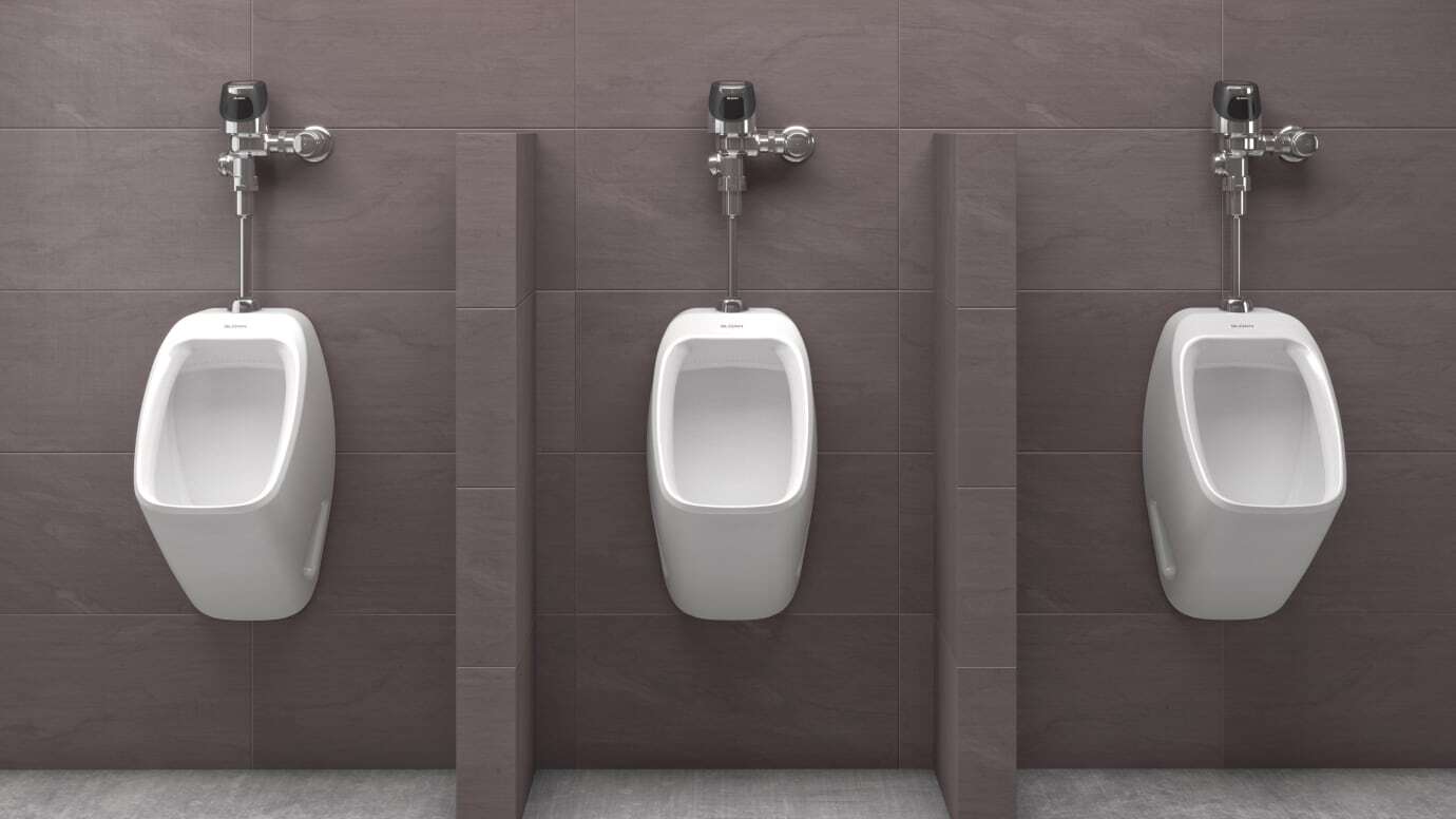 Focused shot of three sensor flushometer urinal combos in a restroom
